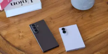Dua unit Galaxy Z Fold 8 dan Z Flip 8 tergeletak di atas meja kayu di sebelah buku dekorasi.