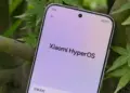 Tampilan layar HP Xiaomi menunjukkan logo Xiaomi HyperOS di menu pengaturan dengan latar belakang daun hijau.
