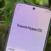 Tampilan layar HP Xiaomi menunjukkan logo Xiaomi HyperOS di menu pengaturan dengan latar belakang daun hijau.