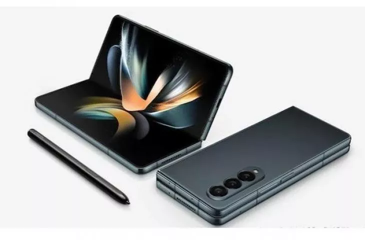 Perangkat smartphone layar lipat (foldable phone) berwarna hitam abu-abu dalam posisi terbuka setengah dan terlipat di samping sebuah stylus pen.
