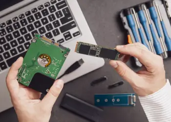 Seseorang sedang membandingkan hardisk laptop internal dengan kepingan modul SSD M.2.