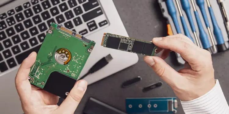 Seseorang sedang membandingkan hardisk laptop internal dengan kepingan modul SSD M.2.
