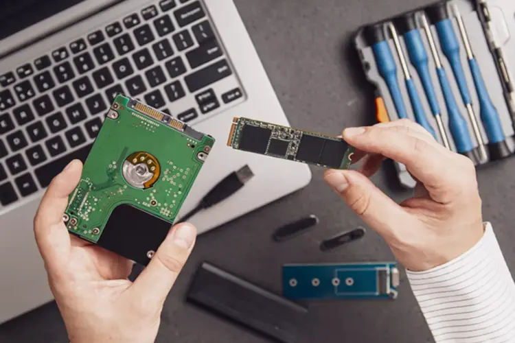 Seseorang sedang membandingkan hardisk laptop internal dengan kepingan modul SSD M.2.