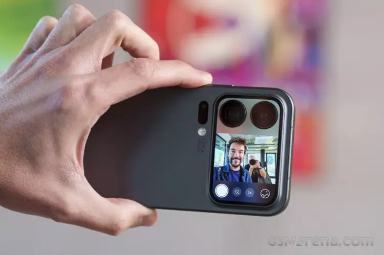 Seseorang memegang Xiaomi 18 Pro Max secara horizontal untuk mengambil foto selfie, menampilkan pratinjau wajah pria tersenyum di layar sekunder belakang ponsel.