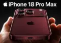 Tangan seseorang memegang iPhone 18 Pro Max warna merah gelap burgundy dengan modul triple camera tebal yang premium.
