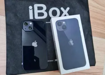 Produk fisik iPhone warna hitam pekat bersanding dengan kotak retail di atas tas belanja iBox resmi