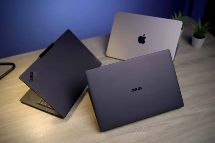 Komparasi fisik ASUS ExpertBook Ultra bersanding dengan Lenovo ThinkPad X1 Carbon di atas meja untuk ulasan laptop ultra premium.
