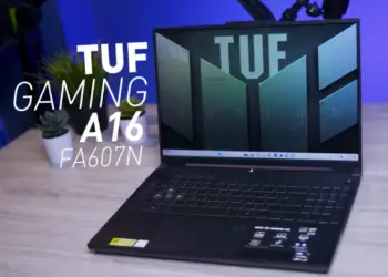 Tampilan depan laptop gaming ASUS TUF A16 FA607N dalam posisi terbuka di atas meja kerja dengan latar cahaya biru studio.