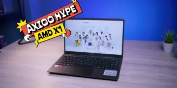 Laptop 5 jutaan terbaik 2026 Axioo Hype AMD X1 tampak depan di atas meja kayu dengan layar Full HD menampilkan wallpaper JKT48.