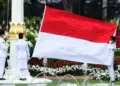 Tiga anggota Paskibraka membentangkan bendera Merah Putih raksasa di tiang bendera Istana Negara.