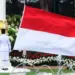Tiga anggota Paskibraka membentangkan bendera Merah Putih raksasa di tiang bendera Istana Negara.
