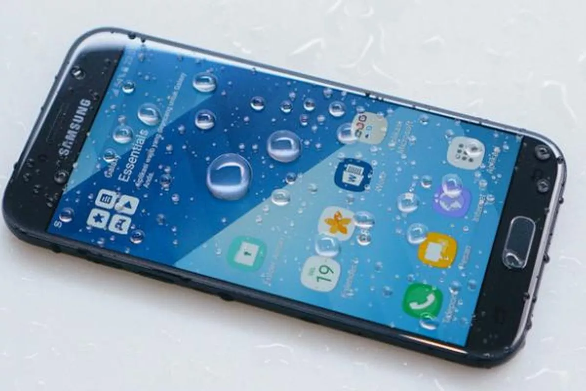 Layar depan HP Samsung tahan air dipenuhi tetesan air yang jernih.