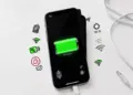 Layar iPhone menampilkan indikator baterai hijau penuh dikelilingi ikon pengaturan konektivitas seperti Wi-Fi dan lokasi.