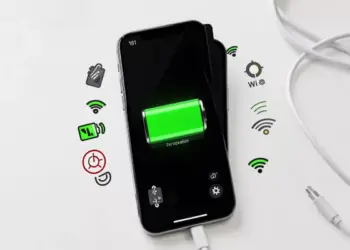 Layar iPhone menampilkan indikator baterai hijau penuh dikelilingi ikon pengaturan konektivitas seperti Wi-Fi dan lokasi.