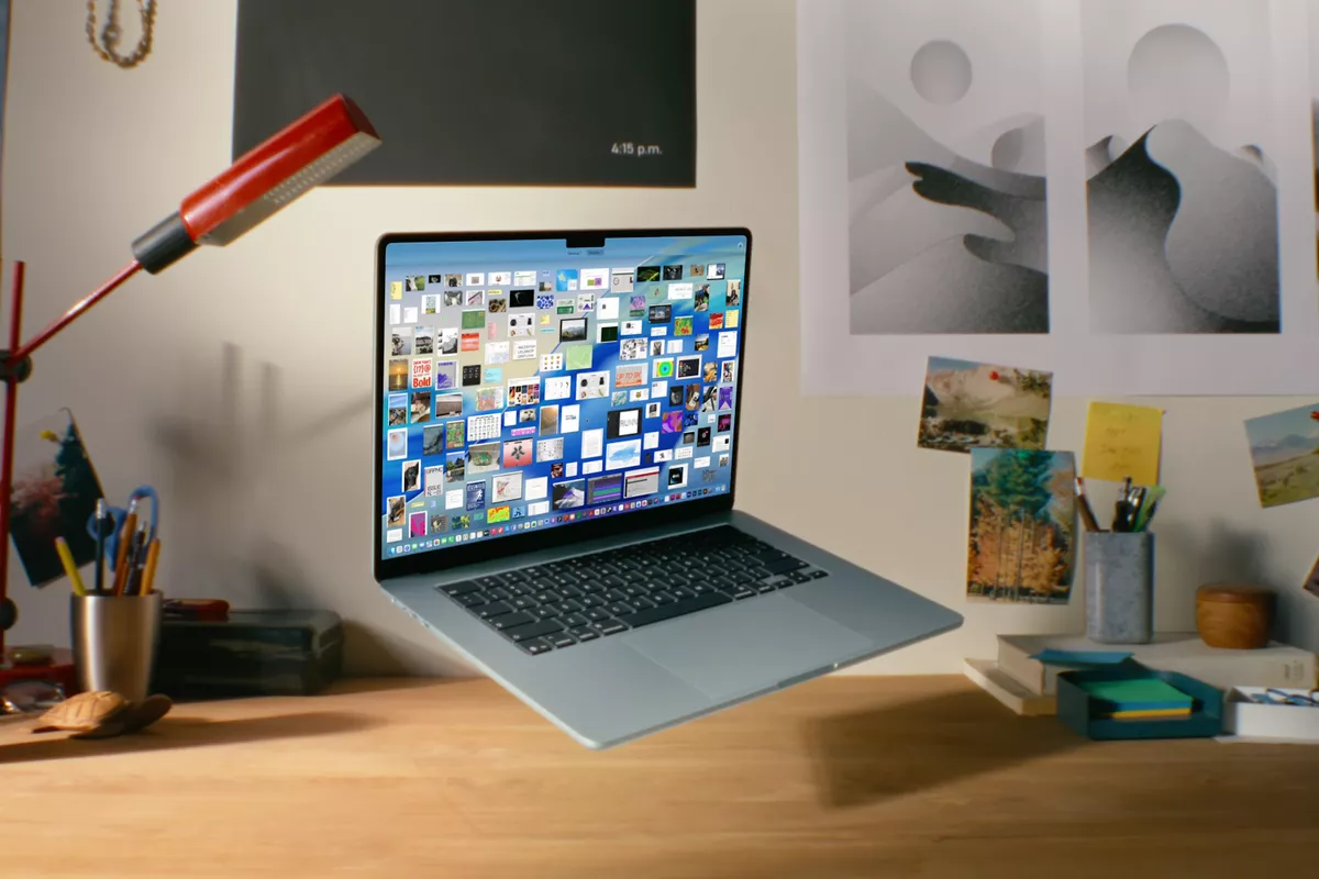 MacBook Air melayang di atas meja kerja dengan layar menampilkan banyak file dan aplikasi.