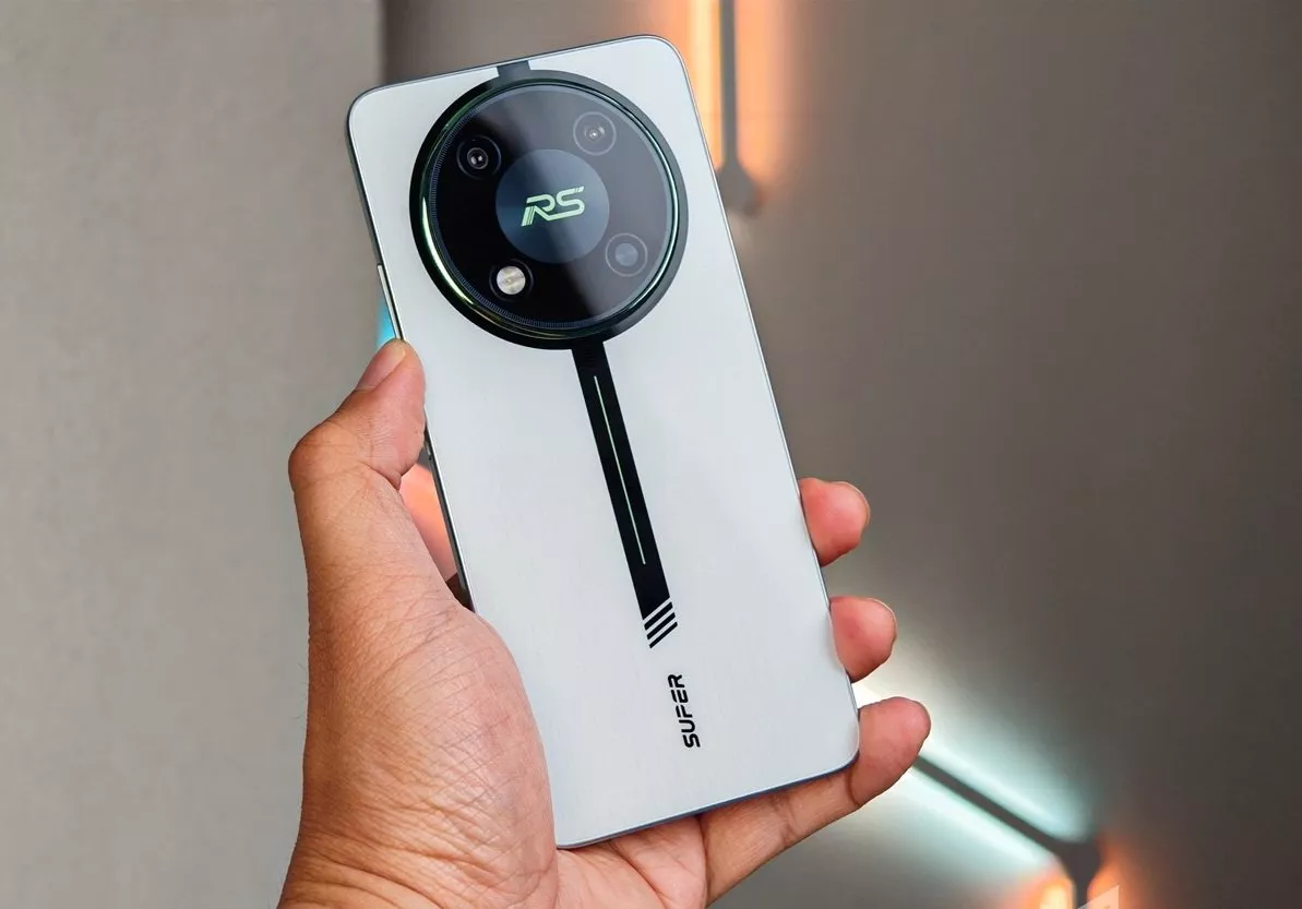 Tangan menggenggam bagian belakang smartphone itel putih dengan modul kamera bulat besar berdesain sporty untuk HP itel RAM Besar.