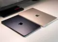 Dua unit MacBook Air tertutup warna Midnight dan Starlight berdampingan di atas meja putih.