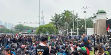 Peserta demo Jakarta duduk tertib di sekitar jalanan dekat gerbang gedung DPR RI.