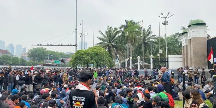 Peserta demo Jakarta duduk tertib di sekitar jalanan dekat gerbang gedung DPR RI.