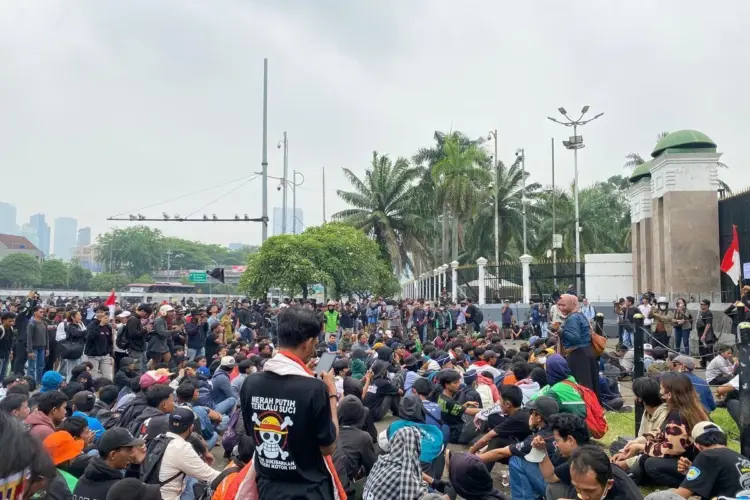 Peserta demo Jakarta duduk tertib di sekitar jalanan dekat gerbang gedung DPR RI.