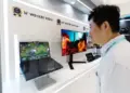 Pengunjung pameran sedang melihat demonstrasi layar Samsung WQ OLED 300Hz pada laptop gaming.