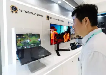Pengunjung pameran sedang melihat demonstrasi layar Samsung WQ OLED 300Hz pada laptop gaming.