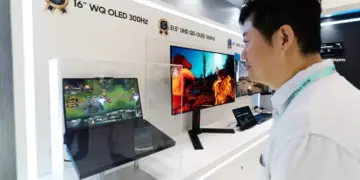 Pengunjung pameran sedang melihat demonstrasi layar Samsung WQ OLED 300Hz pada laptop gaming.