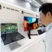 Pengunjung pameran sedang melihat demonstrasi layar Samsung WQ OLED 300Hz pada laptop gaming.