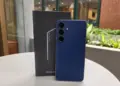 Unit Samsung Galaxy S26 FE warna biru tua berdiri di samping boks penjualan resminya.