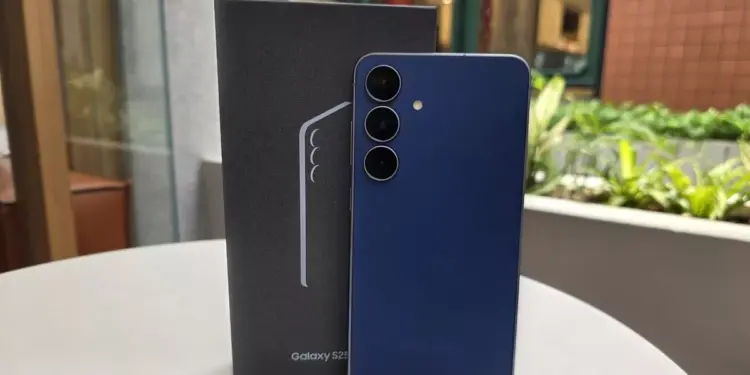 Unit Samsung Galaxy S26 FE warna biru tua berdiri di samping boks penjualan resminya.