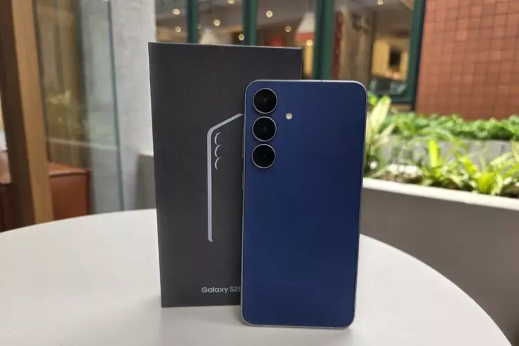 Unit Samsung Galaxy S26 FE warna biru tua berdiri di samping boks penjualan resminya.