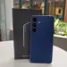Unit Samsung Galaxy S26 FE warna biru tua berdiri di samping boks penjualan resminya.