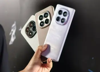 Seseorang menggenggam tiga unit HP Redmi RAM 8 GB dengan bodi elegan dan kamera besar.