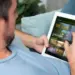 Seseorang sedang santai di sofa menggunakan tablet layar lebar ber-SIM card untuk menonton film.