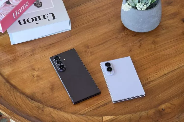 Dua unit Samsung Galaxy Z Fold 8 berwarna gelap dan terang diletakkan di atas meja kayu.