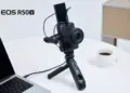 Kamera mirrorless Canon EOS R50 V terpasang pada tripod grip dengan layar terlipat ke atas untuk vlogging.