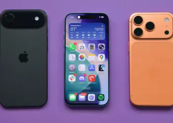 Tiga unit perangkat iPhone dengan varian warna hitam, layar depan aktif, dan warna orange tembaga di atas latar belakang ungu.