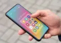 Penggunaan HP Android ukuran compact menggunakan satu tangan di luar ruangan.