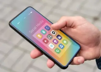 Penggunaan HP Android ukuran compact menggunakan satu tangan di luar ruangan.
