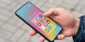 Penggunaan HP Android ukuran compact menggunakan satu tangan di luar ruangan.