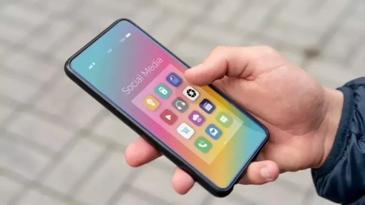 Penggunaan HP Android ukuran compact menggunakan satu tangan di luar ruangan.