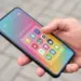 Penggunaan HP Android ukuran compact menggunakan satu tangan di luar ruangan.
