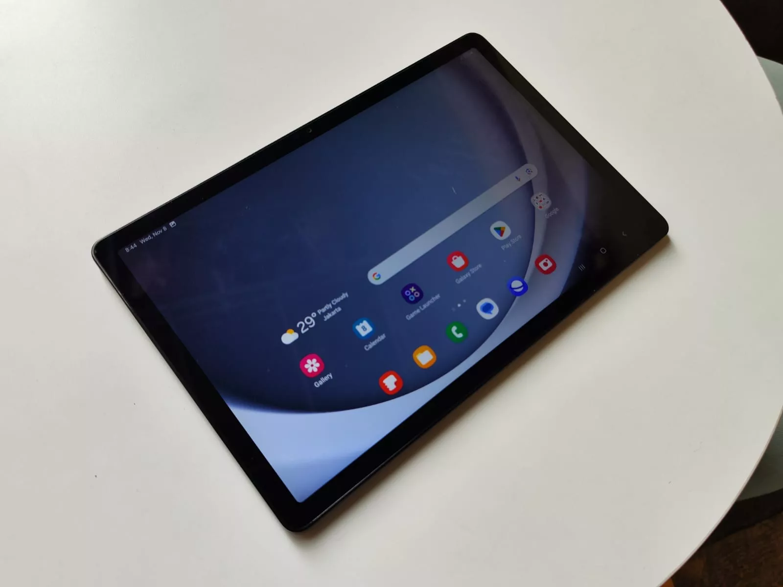 Tablet layar lebar ber-SIM card dengan tampilan antarmuka Android diletakkan di atas meja putih.