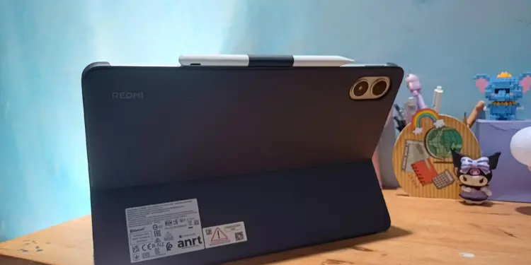 Tablet Xiaomi Terbaik merk Redmi warna hitam terpasang pada casing pendukung stylus di meja kerja