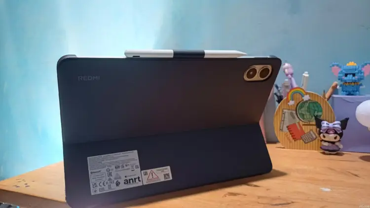 Tablet Xiaomi Terbaik merk Redmi warna hitam terpasang pada casing pendukung stylus di meja kerja