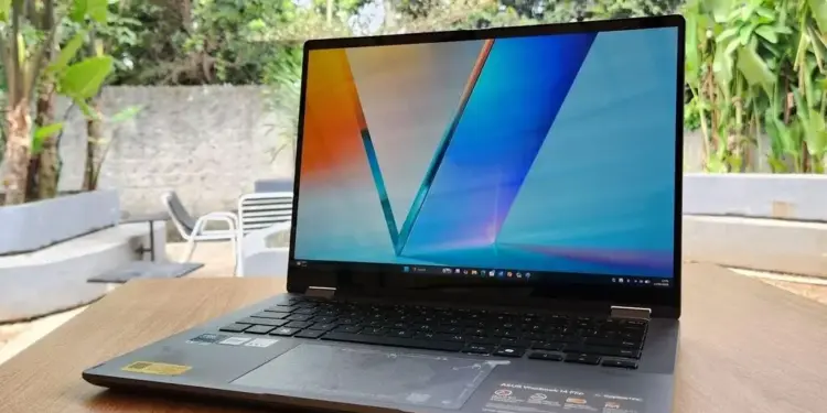 Laptop ASUS Vivobook 14 Flip TP3407AA terbuka di atas meja kayu dengan layar OLED berwarna cerah.