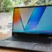 Laptop ASUS Vivobook 14 Flip TP3407AA terbuka di atas meja kayu dengan layar OLED berwarna cerah.
