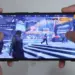 Seseorang sedang bermain game FPS di HP 1 jutaan dengan layar mulus 120Hz.