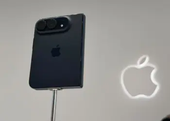 Penampakan bodi belakang iPhone Duo warna hitam terpasang pada stand pameran dengan logo Apple menyala di latar belakang.