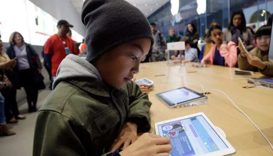Anak sekolah mencoba tablet murah 2026 untuk sekolah di meja pameran toko elektronik